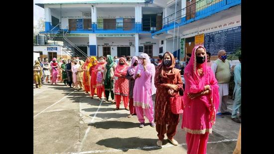 Voters following the Covid-19 guidelines by wearing masks and maintaining social distancing as they queue up for the Dharamshala Municipal Corporation elections on Wednesday. (HT Photo)