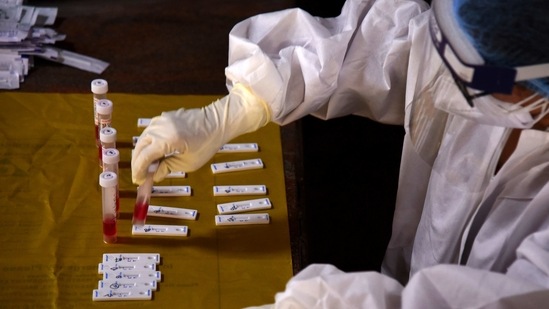 A health worker in PPE tests samples collected for Covid-19 detection from travellers at Vashi Railway Station in Navi Mumbai on April 7. India set another record for daily cases of Covid-19, with 115,320 new infections reported across the country on April 6 — the second time in three days that the country broke previous single-day case records.(Bachchan Kumar / HT Photo)