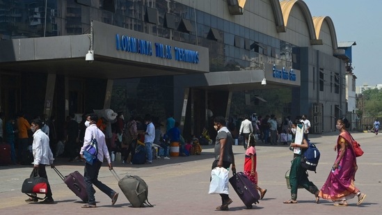Passengers with luggage outside Lokmanya Tilak Terminus railway complex to catch a train amidst rising Covid-19 cases in Mumbai on April 6. By afternoon on the first day of the new Covid-19 restrictions, a majority of Mumbai wore a deserted look as shops closed down and most people left the streets, HT reported.(Indranil Mukherjee / AFP)