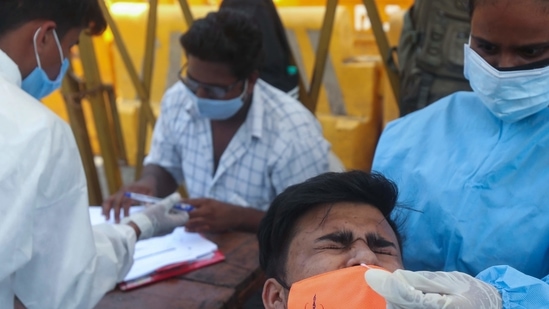 A health worker takes a nasal swab sample of a man to test for COVID-19 in Mumbai (AP)