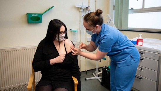 Elle Taylor (L), 24, an unpaid carer from Ammanford, receives an injection of the Moderna Covid-19 vaccine in Wales. (AFP) Elle Taylor (L), 24, an unpaid carer from Ammanford, receives an injection of the Moderna Covid-19 vaccine in Wales. (AFP)