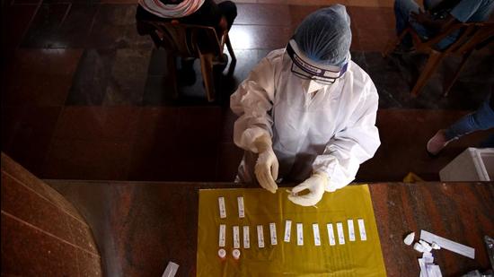 A health worker in PPE testing samples taken for Covid-19 detection. (HT PHOTO)