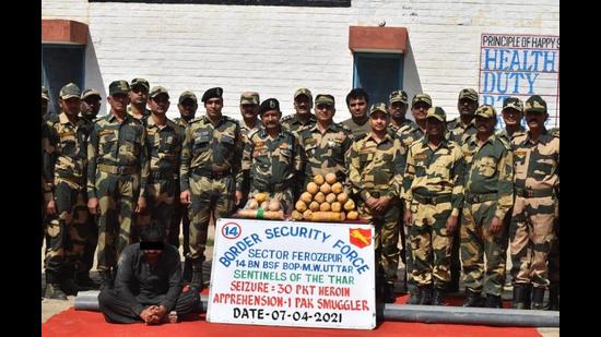 BSF personnel with the contraband seized from the Pakistani smuggler along the border at Khemkaran in Tarn Taran on Wednesday. (HT Photo) BSF personnel with the contraband seized from the Pakistani smuggler along the border at Khemkaran in Tarn Taran on Wednesday. (HT Photo)