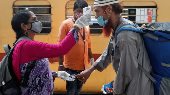 A health worker checks a passenger's temperature and pulse at a railway station in Mumbai.(Reuters)