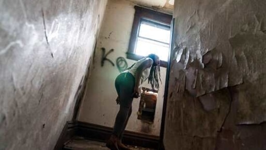 Larrecsa Cox peers around a stairwell while walking through an abandoned home frequented by people struggling with addiction.(AP) Larrecsa Cox peers around a stairwell while walking through an abandoned home frequented by people struggling with addiction.(AP)