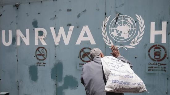 In this file photo, a Palestinian man standing in front of the emblem of the UN Relief and Works Agency for Palestine Refugees in the Near East (UNRWA) outside the agency's offices in Gaza City. (AFP)