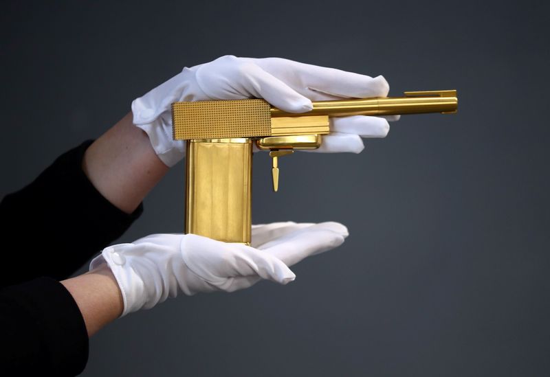 An auctioneer specialist holds a James Bond 'The Man With The Golden Gun' 24 carat gold-plated replica gun. (REUTERS)