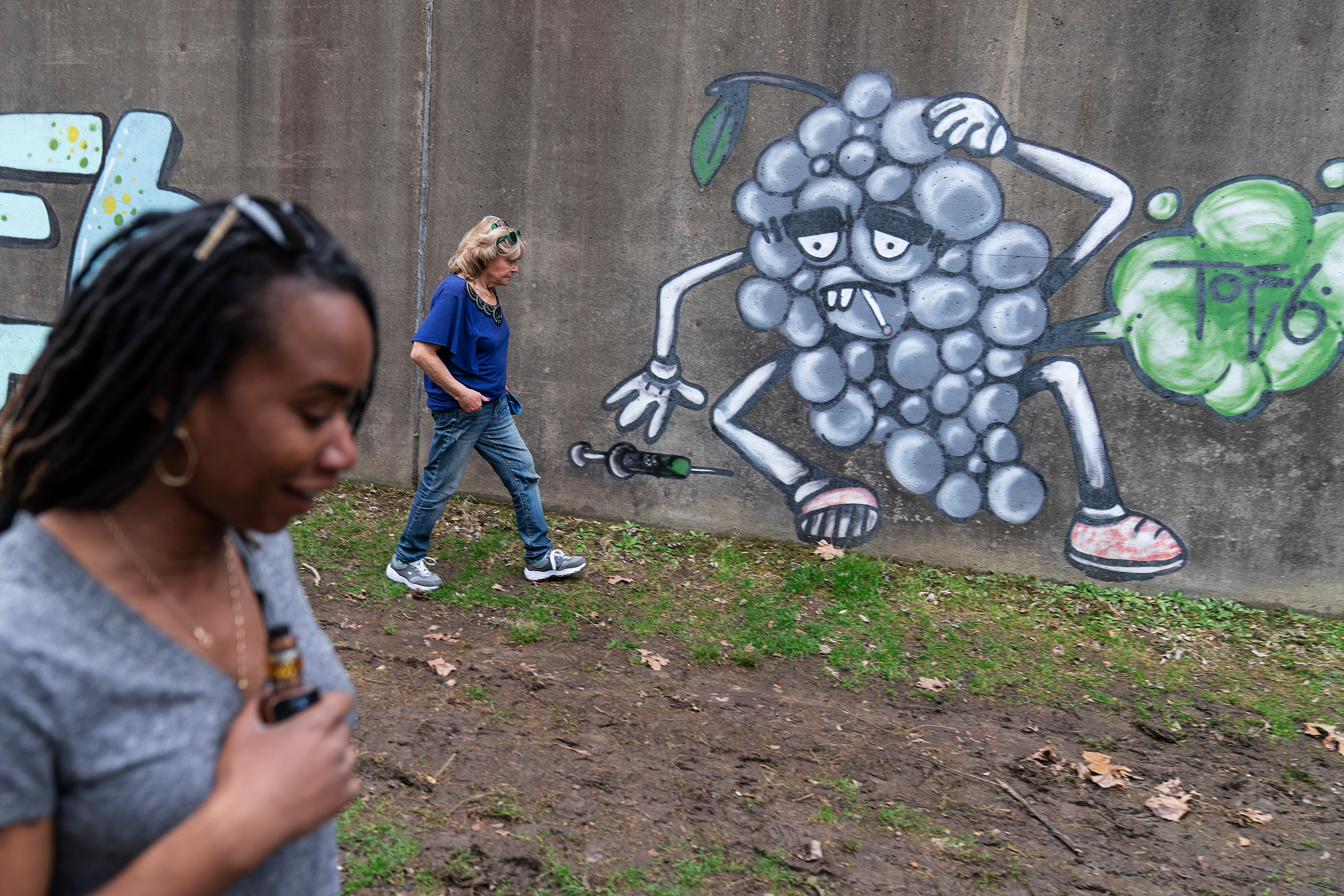 Larrecsa Cox, foreground, and Sue Howland with the Quick Response Team, walk past addiction-themed graffiti.(AP) Larrecsa Cox, foreground, and Sue Howland with the Quick Response Team, walk past addiction-themed graffiti.(AP)