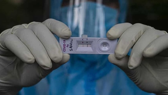 A health worker shows a sample kit of a COVID-19 positive test during a door to door test drive.(AP)