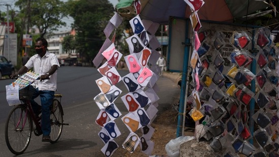 A lottery ticket vendor wearing a mask as a precaution against the coronavirus pedals his bicycle past face masks displayed for sale by a roadside in Kochi on April 11. India recorded 1,52,879 new cases of Covid-19 on April 11 according to the health ministry's update., hitting another record in the daily tally of cases. (R S Iyer / AP) A lottery ticket vendor wearing a mask as a precaution against the coronavirus pedals his bicycle past face masks displayed for sale by a roadside in Kochi on April 11. India recorded 1,52,879 new cases of Covid-19 on April 11 according to the health ministry's update., hitting another record in the daily tally of cases. (R S Iyer / AP)
