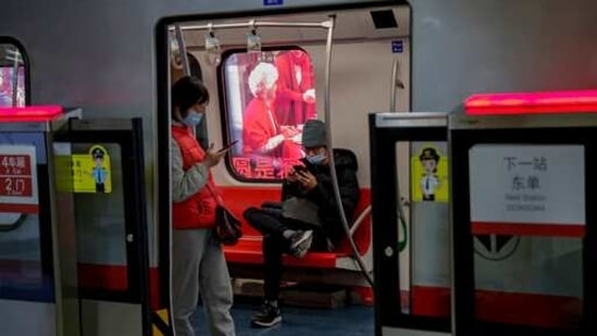 Commuters wearing face masks browse their smartphones inside a subway train in Beijing.(AP)