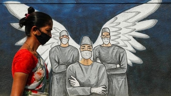 A woman wearing a face mask walks past a Covid-19 graffiti in Navi Mumbai.(Francis Mascarenhas / Reuters) A woman wearing a face mask walks past a Covid-19 graffiti in Navi Mumbai.(Francis Mascarenhas / Reuters)