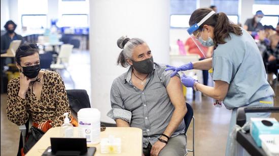 Jules Mccusker receives a BioNTech Pfizer Covid-19 vaccine from Dr Shauna Martiniuk, in Toronto, on Saturday. (AP) Jules Mccusker receives a BioNTech Pfizer Covid-19 vaccine from Dr Shauna Martiniuk, in Toronto, on Saturday. (AP)
