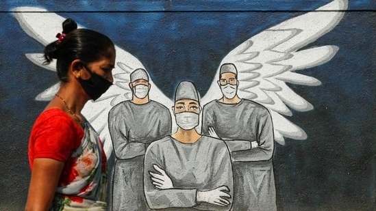 A woman wearing a face mask walks past a Covid-19 graffiti in Navi Mumbai. (Francis Mascarenhas / Reuters) A woman wearing a face mask walks past a Covid-19 graffiti in Navi Mumbai. (Francis Mascarenhas / Reuters)