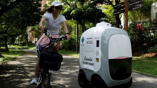 A cyclist passes as Camello, an autonomous grocery delivery robot, makes its way during a delivery in Singapore.(REUTERS)