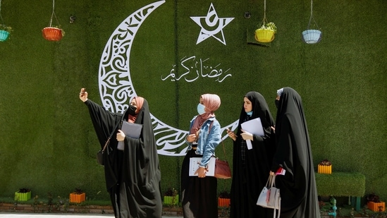 Women take a selfie next to a crescent, ahead of the holy fasting month of Ramadan, in Najaf, Iraq, April 12, 2021. (REUTERS)