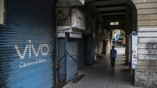 A pedestrian walks past closed stores during a weekend lockdown, in the deserted Fort area of Mumbai.(Bloomberg) A pedestrian walks past closed stores during a weekend lockdown, in the deserted Fort area of Mumbai.(Bloomberg)