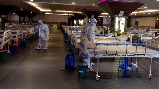 Health workers in PPE coveralls sanitise the premises inside the temporary Covid Care facility, at Shehnai Banquet, in New Delhi, on April 12. The number of people who have recovered from the coronavirus disease surged to 1,21,56,529, on April 12 while the case fatality rate has further dropped to 1.26 %, the PTI reported citing Union Health Ministry data.(Sanjeev Verma / HT Photo)