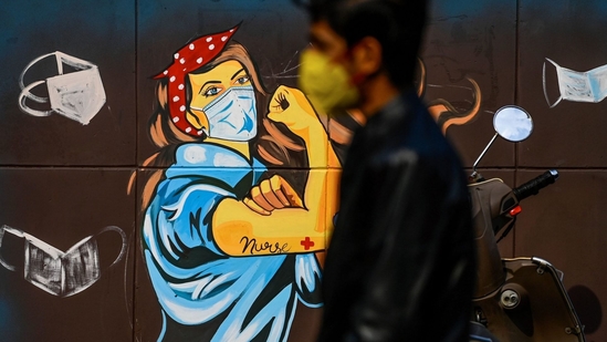 A man wearing a facemask as a preventive measure against the Covid-19 coronavirus walks past a mural in New Delhi, India.(Sajjad Hussain/AFP via Getty Images)