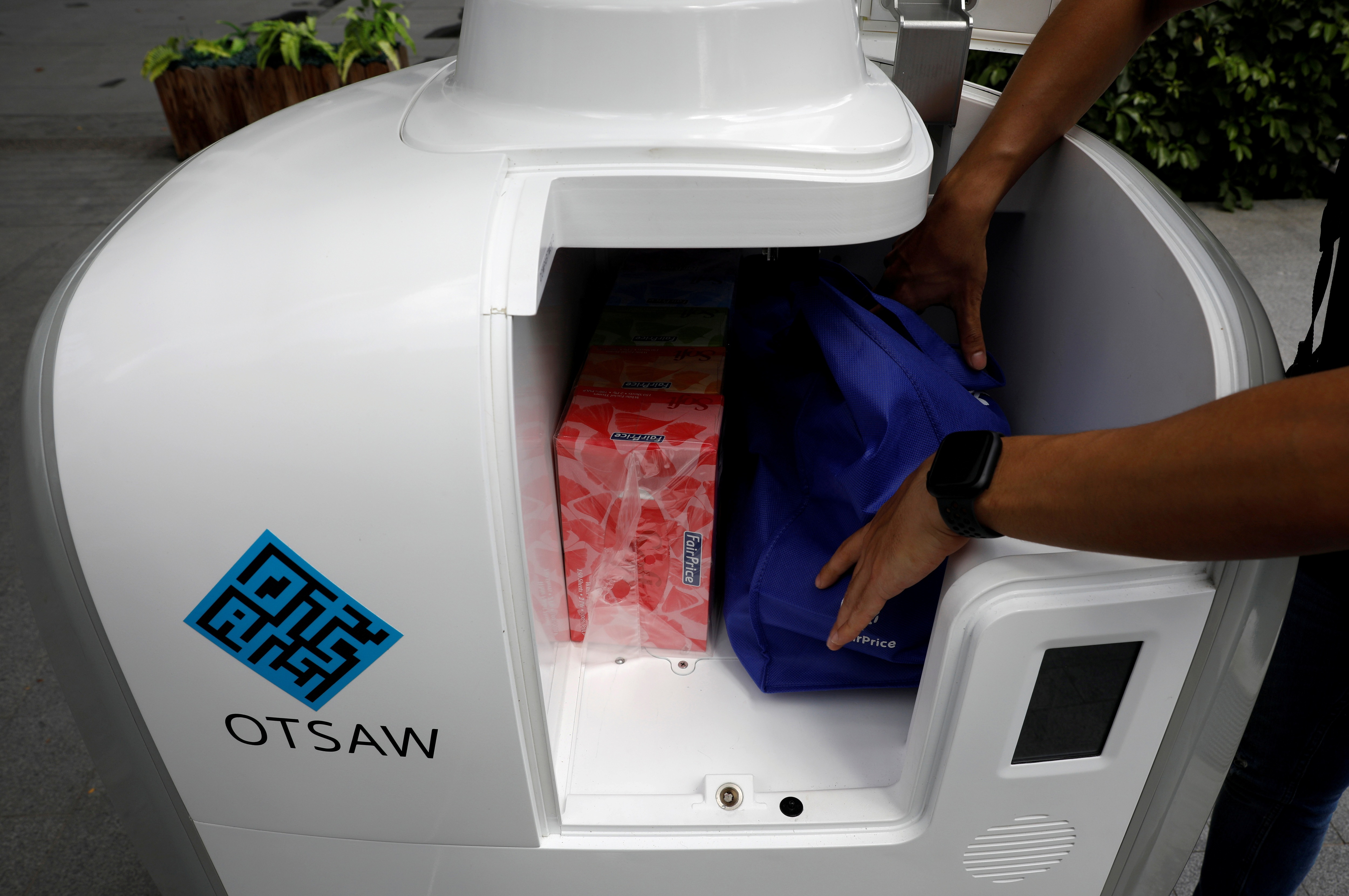 A staff member loads groceries into Camello, an autonomous grocery delivery robot, in Singapore. (REUTERS)