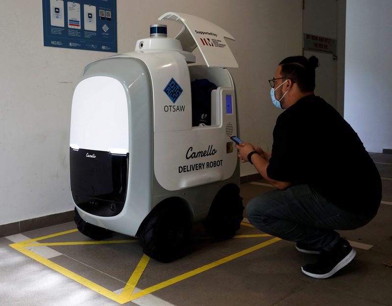 A customer collects his groceries from Camello, an autonomous grocery delivery robot, in Singapore (REUTERS)