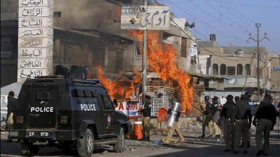 Karachi police officers confront angry supporters of Tehreek-e-Labiak Pakistan (TLP), a radical Islamist political party, who set fires during Tuesday’s protests following the arrest of their party leader Saad Rizvi (AP)