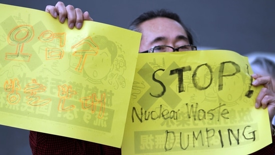 A man holds placards that read "Oppose to release contaminated water," left, and "Stop Nuclear Waste Dumping" during a protest rally against government's decision, outside the prime minister's office in Tokyo Tuesday, April 13, 2021. Japan's government decided Tuesday to start releasing treated radioactive water from the wrecked Fukushima nuclear plant into the Pacific Ocean in two years, an option fiercely opposed by fishermen, residents and Japan's neighbors. (AP Photo/Eugene Hoshiko)(AP)