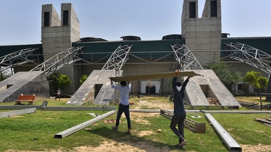 Workers setting up a temporary quarantine facility for Covid-19 patients at CWG village in New Delhi on April 14. With cases charting upwards, Chief Minister of Delhi Arvind Kejriwal on April 15 announced that a weekend curfew was being added to existing curbs imposed to arrest the number of infections.(Sanchit Khanna / HT Photo)
