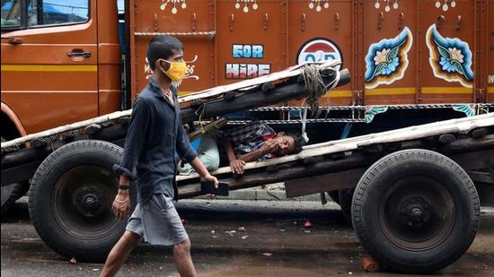 A man walks past a labourer resting on a handcart in a closed wholesale market amid a lockdown in Kolkata last year. (File photo)