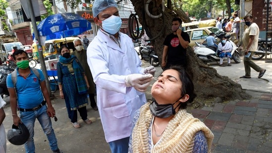 A health worker collects swab sample from a woman for Covid-19 test in Delhi. (PTI)