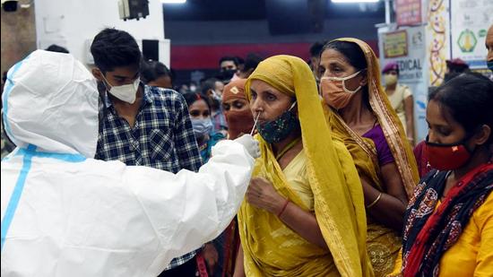 A medic wearing a PPE kit takes a nasal sample of a migrant for Covid-19 testing amid the surge in cases at Patna Junction railway station on Thursday. (ANI PHOTO.) A medic wearing a PPE kit takes a nasal sample of a migrant for Covid-19 testing amid the surge in cases at Patna Junction railway station on Thursday. (ANI PHOTO.)