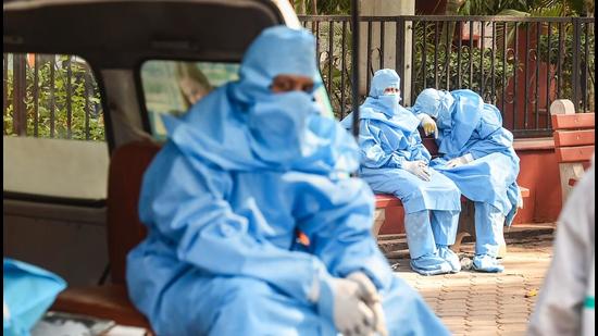 Family members wearing PPE kits, wait during the cremation of a COVID-19 victim at the Nigambodh Ghat in New Delhi on Friday. (PTI PHOTO.) Family members wearing PPE kits, wait during the cremation of a COVID-19 victim at the Nigambodh Ghat in New Delhi on Friday. (PTI PHOTO.)
