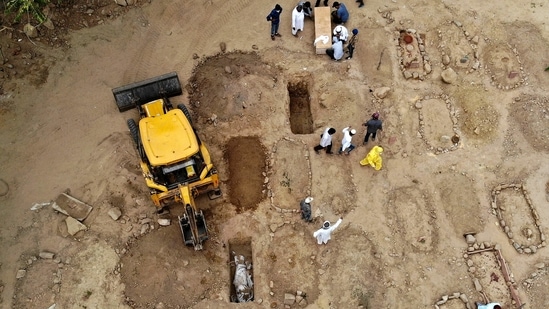 Relatives and friends gather to bury the dead bodies of Covid-19 victims at a graveyard in New Delhi on April 16. With more bodies arriving at the burial ground, officials of the ITO graveyard--one of the largest burial grounds in Delhi--have brought in earth movers to dig several graves.(Archana Thiyagarajan / AFP)