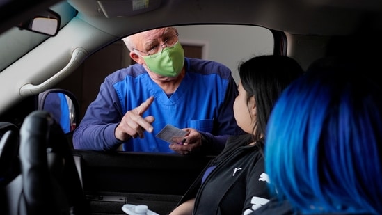 Volunteer Rick Champany gives vaccination cards to Yessica Guerra and Jahelin Duran after they received coronavirus disease (Covid-19) vaccines at a rural vaccination site in Columbus, New Mexico, US. (Reuters Photo)