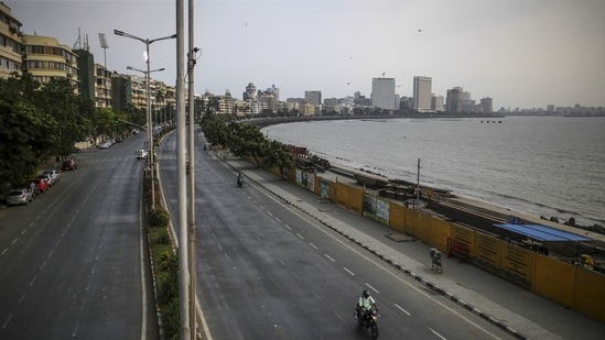 A motorcyclist travels along a deserted Marine Drive during a weekend lockdown in Mumbai.(Bloomberg)