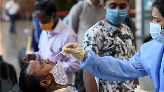 A health worker takes swab samples from a passenger at Chhatrapati Shivaji Maharaj Terminus Railway Station, amid spike in Covid-19 cases in Mumbai, Friday. (PTI Photo ) A health worker takes swab samples from a passenger at Chhatrapati Shivaji Maharaj Terminus Railway Station, amid spike in Covid-19 cases in Mumbai, Friday. (PTI Photo )