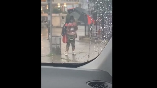 The image shows the woman holding an umbrella she received from a good samaritan.(Screengrab)