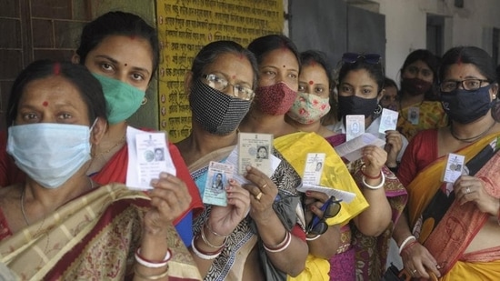 Women show their voter ID cards as they stand in a queue to cast their vote at a polling station during the 5th phase of West Bengal assembly polls.