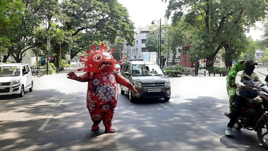 A man wearing a Covid-19 costume performs on the road to create awareness about the Covid-19 vaccination in Pune on Sunday. (ANI Photo)