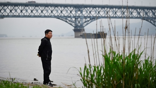 Chen looks out from the riverside of the Yangtze river, with the Nanjing Bridge in the background, in Jiangsu province, on April 1. The father-of-one said voluntary work has come at a cost to his personal life. "I didn't do this alone. It was time that I borrowed from my wife and my child," he told AFP, adding his wife had taken the brunt of childcare.(Wang Zhao / AFP)