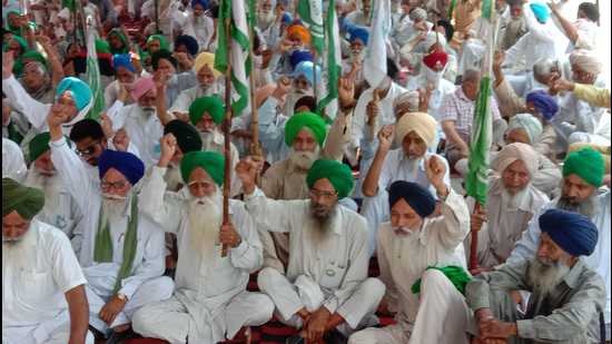 Farmers staging a protest at the railway station parking in Barnala on Sunday.