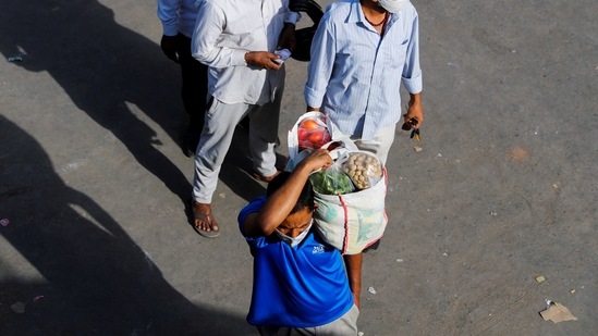 A man carrying vegetables stands in a queue after Delhi government ordered a six-day lockdown to limit the spread of the coronavirus disease in New Delhi. (REUTERS) A man carrying vegetables stands in a queue after Delhi government ordered a six-day lockdown to limit the spread of the coronavirus disease in New Delhi. (REUTERS)
