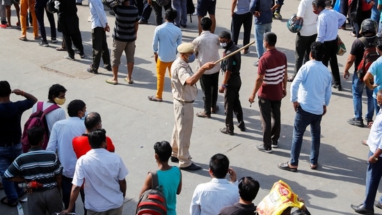 A police officer tries to control a crowd outside a wine store after Delhi government ordered a six-day lockdown. (REUTERS)