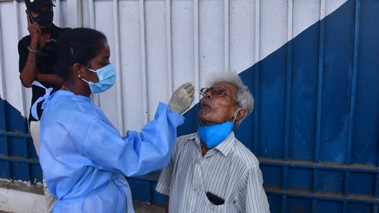 Mumbai, India – April 19, 2021: A health worker collects a swab sample from a traveler, at Dadar Station, in Mumbai, India, Monday, April 19, 2021. (Photo by Bhushan Koyande/ HT Photo)
