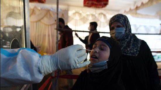 A health worker takes a swab sample of a girl at a test centre in Srinagar on Monday. (Waseem Andrabi/HT) A health worker takes a swab sample of a girl at a test centre in Srinagar on Monday. (Waseem Andrabi/HT)