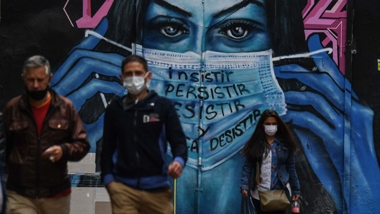 People walk past a mural depicting a woman wearing a face mask in Bogota, Colombia. (AFP) People walk past a mural depicting a woman wearing a face mask in Bogota, Colombia. (AFP)