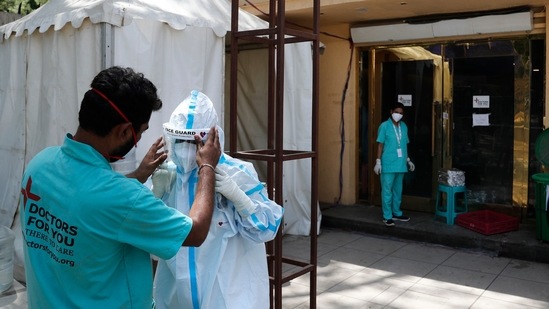 A health worker adjusts the face shield of another as she prepares to go inside a quarantine center for Covid-19 patients in New Delhi on April 19. The latest in the series of grim landmarks for the country comes only 10 days after active cases in the country crossed the 1 million active cases mark on April 10.(Manish Swarup / AP)