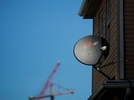A Dish Network receiver hangs on a house in Somerville, Massachusetts.