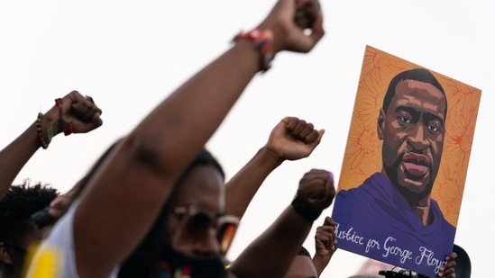 People raise their fists and hold a portrait of George Floyd during a rally following the guilty verdict the trial of Derek Chauvin on April 20 in Atlanta, Georgia.(Elijah Nouvelage / AFP)