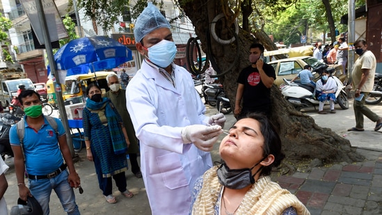 A health worker collects swab sample from a woman for Covid-19 test in Delhi. (PTI) A health worker collects swab sample from a woman for Covid-19 test in Delhi. (PTI)